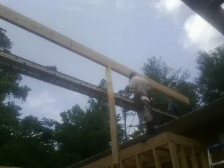 Carpenter setting a ridge beam over a new addition frame — Ice Dam Removal by Roofing Brothers in Gilman
