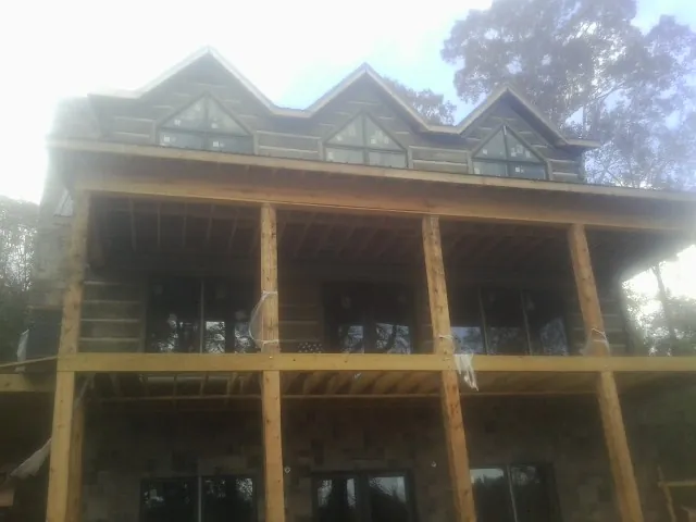 Dormers and porch framing on a large log home under construction — Roof Coating work by our crew in Gilman