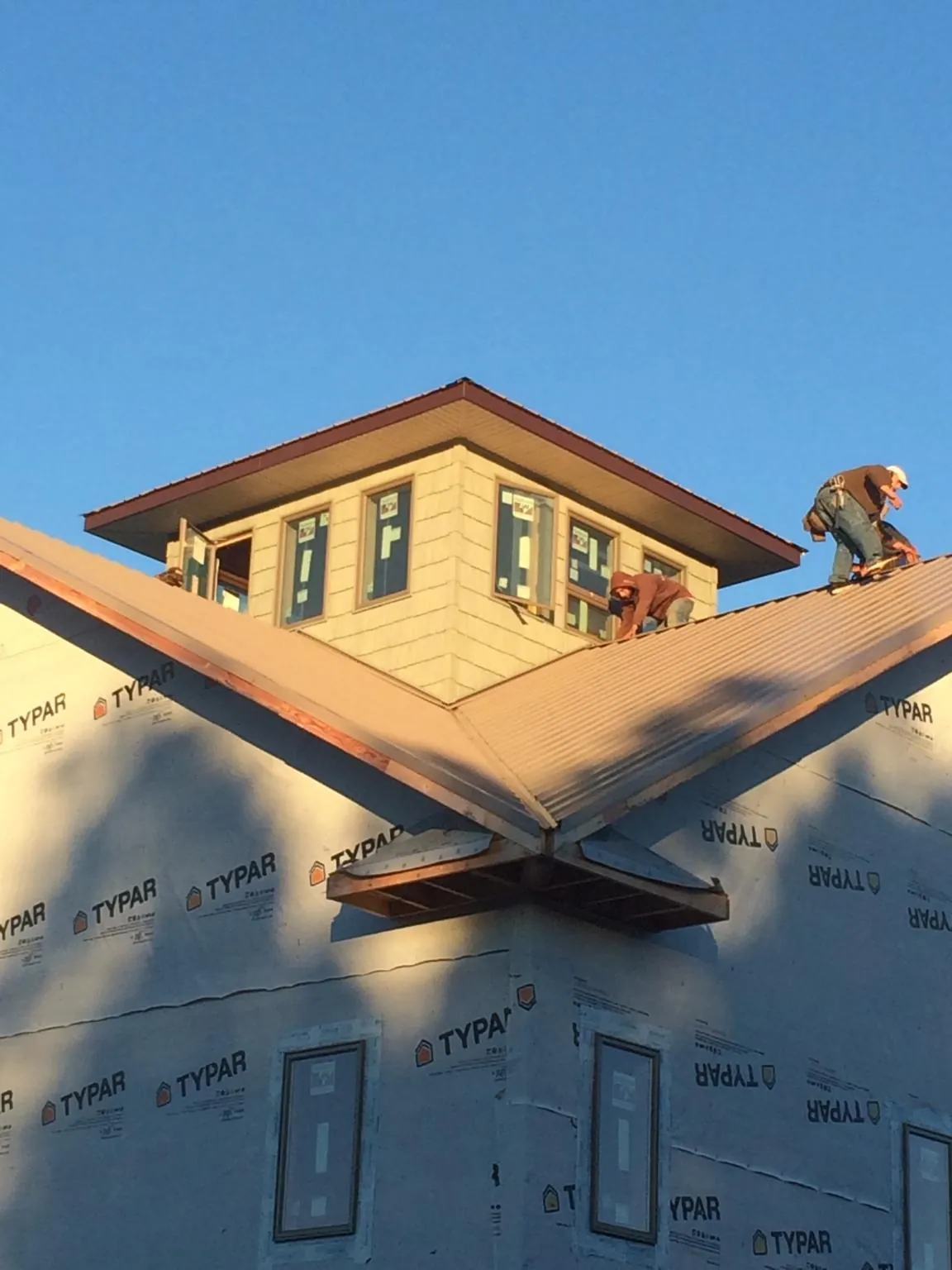 Roofers working around a rooftop cupola on a new metal roof at sunset — Roof Waterproofing in Gilman by Roofing Brothers